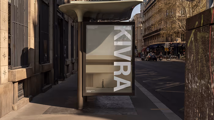 Bus stop shelter on a city sidewalk with a vertical advertisement reading 'KIVRA' in large white letters.