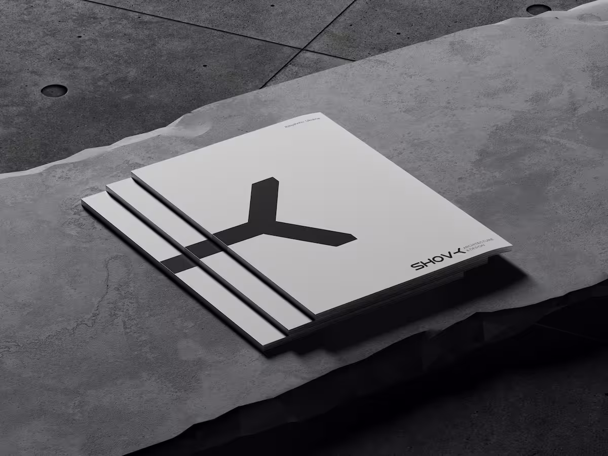 Stack of three grey architectural design journals with a minimalist black Y-shaped design on the cover, placed on a textured stone surface.